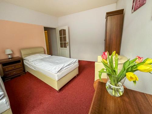 a bedroom with a bed and a vase of flowers on a table at Hotel Růžek in Hranice