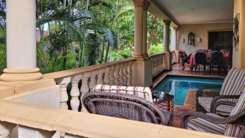 een veranda met stoelen en een zwembad bij Casa Alegre Guesthouse in Southbroom