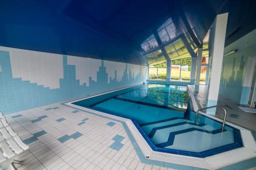 a large swimming pool in a house with a building at Hotel Elsyn Dvůr in Stachy