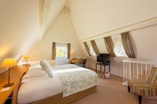 a bedroom with a large bed and a desk at Les Manoirs de Tourgéville in Deauville
