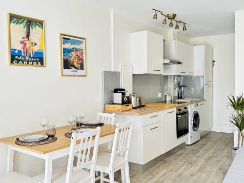 une cuisine avec des armoires blanches et une table et des chaises dans l'établissement Le Palm Beach - Bord de mer - Cannes, à Cannes