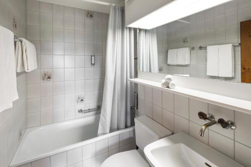 La salle de bains est pourvue d'une baignoire, d'un lavabo et de toilettes. dans l'établissement Hotel und Naturhaus Bellevue, à Seelisberg