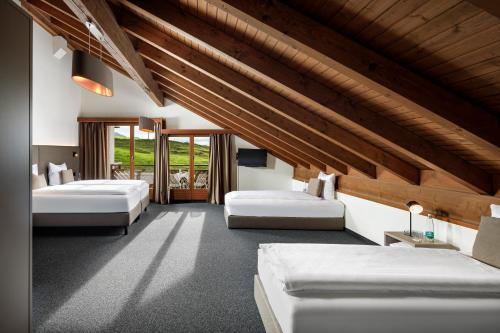 a bedroom with two beds and a wooden ceiling at Hotel und Naturhaus Bellevue in Seelisberg