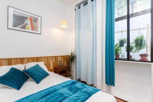 une chambre avec un lit avec des oreillers bleus et une fenêtre dans l'établissement Île St Louis-Bastille-3BRD-Paris 4è, à Paris