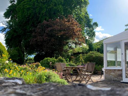 a patio with a table and chairs in a garden at Cynynion Uchaf - Countryside Farmhouse with Views in Oswestry