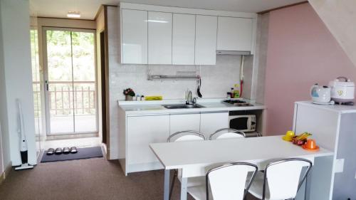 a kitchen with white cabinets and a table and chairs at Dreaming Forest Pension Seogwipo in Seogwipo