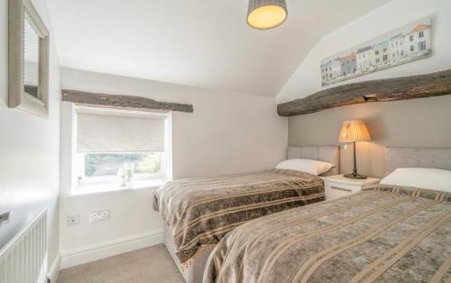 a bedroom with two beds and a window at L'al Cottage, Sockbridge in Penrith