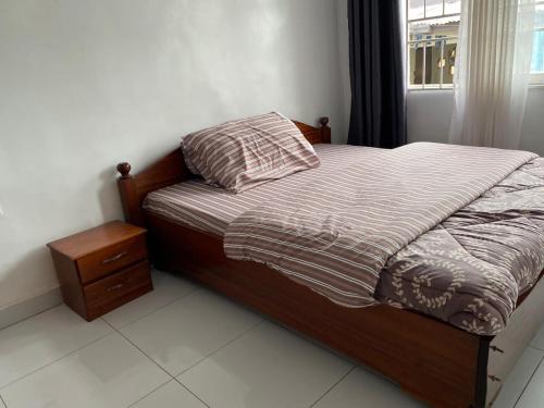 BIZI HOMES في كيغالي: غرفة نوم بسرير وموقف ليلي ونافذة