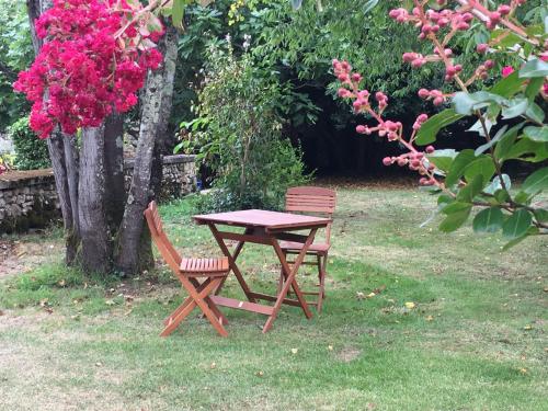 een picknicktafel en twee stoelen in een tuin met bloemen bij Au cœur du jardin in Souvigné