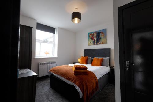sypialnia z łóżkiem z pomarańczowymi poduszkami i oknem w obiekcie Victoria Apartments w Skegness