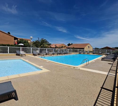 une grande piscine entourée de bancs dans l'établissement Maison entre la mer et la Clape, à Narbonne-Plage