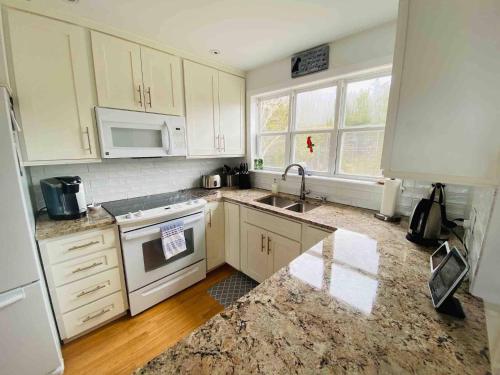 a kitchen with white cabinets and a sink at The Carriage House - Tranquility With A View in LʼEtête