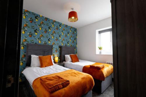 sypialnia z 2 łóżkami i pomarańczową pościelą w obiekcie Victoria Apartments w Skegness