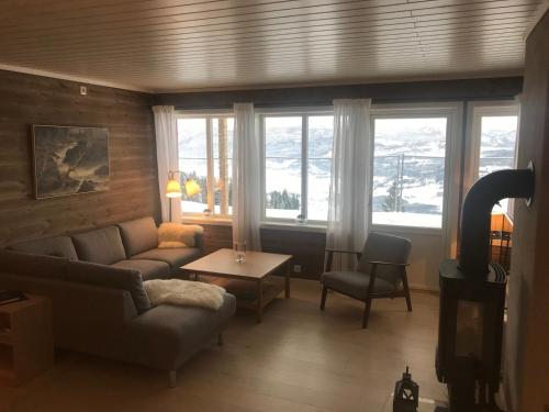 ein Wohnzimmer mit einem Sofa, einem Tisch und Fenstern in der Unterkunft Voss Resort Bavallstunet in Skulestadmo