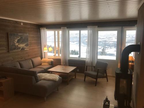 a living room with a couch and a table and windows at Voss Resort Bavallstunet in Skulestadmo
