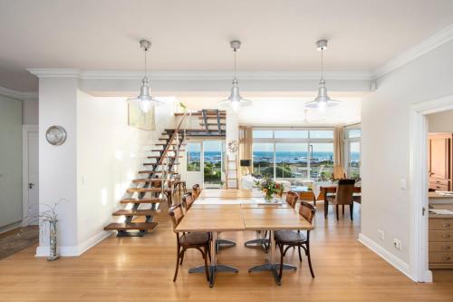 a dining room with a table and a spiral staircase at 138 Marine Beachfront Guesthouse in Hermanus