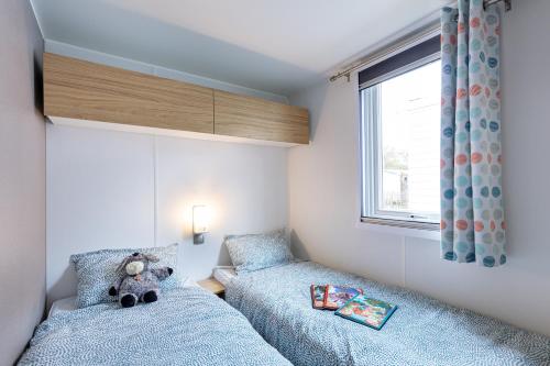 - une petite chambre avec 2 lits et un ours en peluche dans l'établissement Mobil home, piscine chauffée, toboggan, accès plage direct - 3 chambres 6 personnes, à La Turballe
