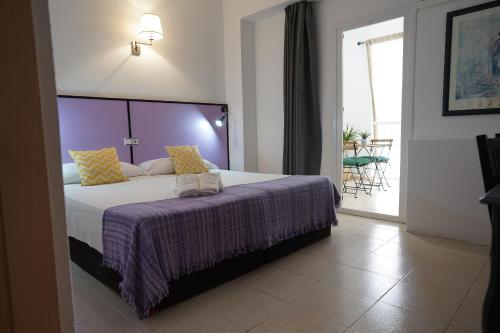 um quarto com uma cama grande e um cobertor roxo em Hotel Teide em El Arenal