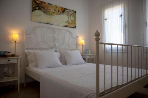 a white bed with white pillows and a painting on the wall at Veloudi's Apartment 1 in Megalochori