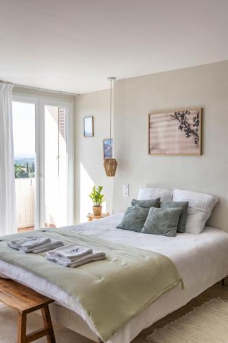 une chambre blanche avec un grand lit et une fenêtre dans l'établissement VUE 180°, superbe appartement cocooning !, à Laroque-des-Albères