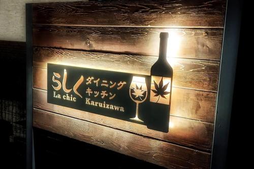 a bottle of wine sign on a wooden wall at Oiwake House 1A in Karuizawa