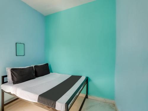 a bed in a room with a blue wall at SPOT ON Hotel Ik Recedency in Chandrapur