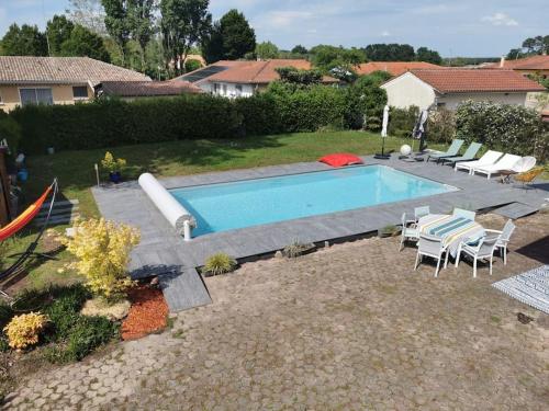 une piscine dans une cour avec des chaises autour dans l'établissement Villa Camelia proche Hossegor, à Bénesse-Maremne