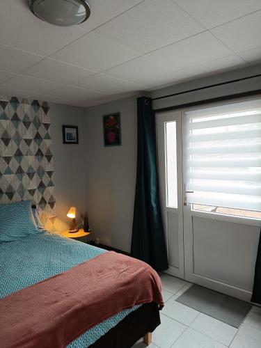 une chambre avec un lit et une porte coulissante en verre dans l'établissement l'accueil, à Guéron