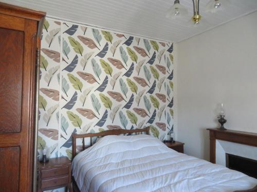 - une chambre avec un lit et un mur recouvert de papier peint dans l'établissement Les gites de Marcel, à Marcillac-la-Croisille