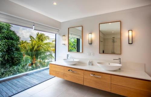 a bathroom with two sinks and a large window at Penthouse Luxueux avec Piscines, Vues Mer et Montagne in Rivière Noire