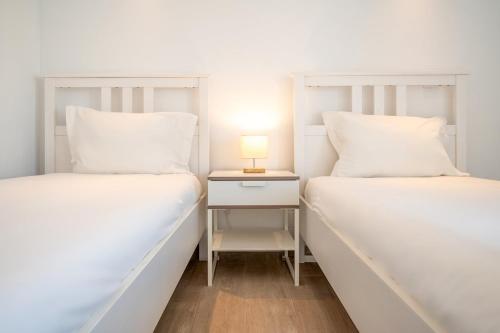 two beds in a room with a lamp on a night stand at GuestReady - Sunny Retreat in Costa da Caparica in Costa da Caparica