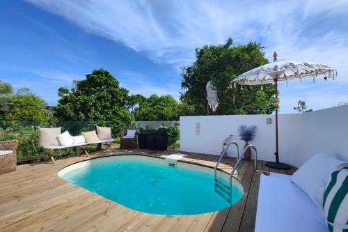 a swimming pool on a wooden deck with an umbrella at Unique Villa Near Lisbon with Pool & Magical Decor in Cheira Ventos