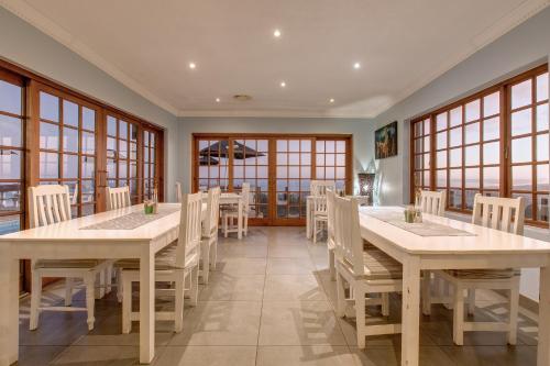 a dining room with tables and chairs and windows at Garden Route Ilita Lodge in Groot Brak Rivier