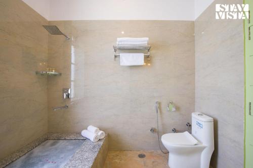a bathroom with a toilet and a shower with towels at The Pastel Courtyard with Pvt Pool & Garden at Jaipur by StayVista in Jaipur