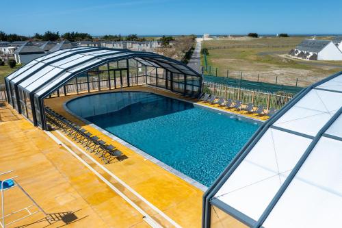 une vue aérienne d'une piscine dans une maison de verre dans l'établissement Mobil home, piscine chauffée, toboggan, accès plage direct - 3 chambres 6 personnes, à La Turballe