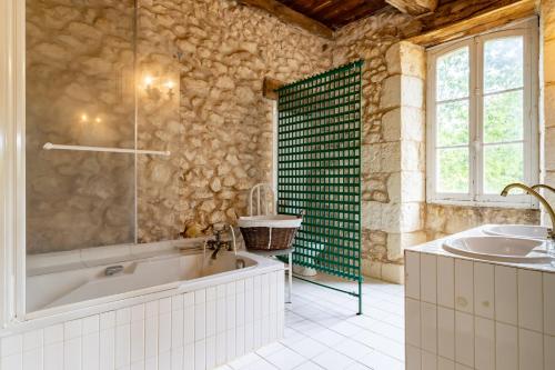 ein großes Bad mit einer Badewanne und einem Waschbecken in der Unterkunft La Jembertie en Périgord in Grignols