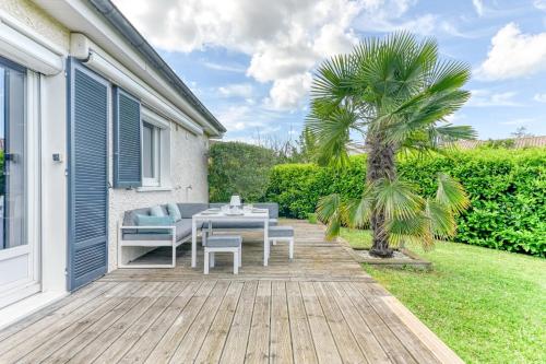 a patio with a table and chairs and a palm tree at Maison des Platanes - Welkeys in Lissieu