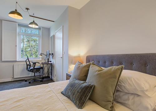 a bedroom with a bed with a desk and a chair at Stylish, business traveller friendly apartment, with free parking and Netflix in Farnborough