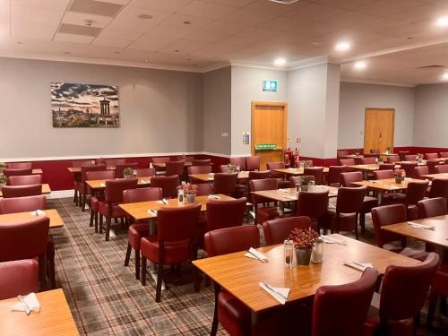 uma sala de jantar com mesas e cadeiras de madeira em Britannia Edinburgh Hotel em Edimburgo