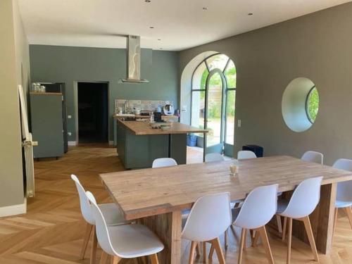 a dining room with a wooden table and white chairs at Magnanerie en plein cœur d'un village in Collias