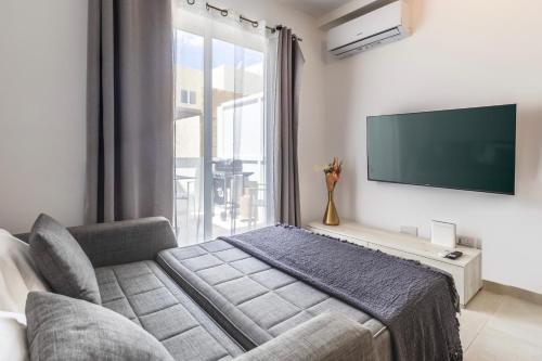 een slaapkamer met een bank en een tv aan de muur bij Dorris's Apartment 5 min walk from St Julians in San Ġwann
