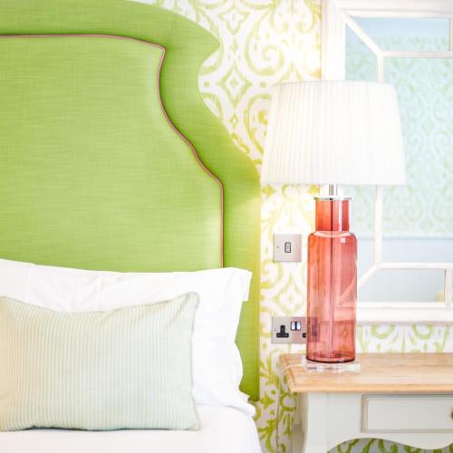 a bedroom with a green headboard and a red lamp on a table at The Swan Hotel and Spa in Newby Bridge