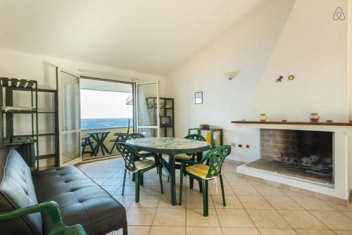 een woonkamer met een tafel en stoelen en een open haard bij Sardegna Incontaminata Apartments SUPER VISTA MARE in Torre Dei Corsari