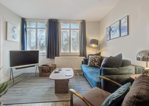 a living room with a blue couch and a tv at Stylish, business traveller friendly apartment, with free parking and Netflix in Farnborough