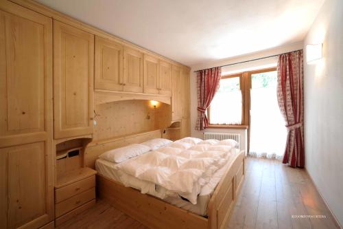 a bedroom with a large bed with a large window at Appartamenti da Nica e Diego in Borca di Cadore