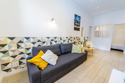 un salon avec un canapé bleu avec des coussins jaunes dans l'établissement Cozy Apartement - Near train Station - Les Frères de la Loc', à Marseille