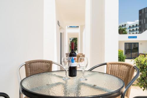 a glass table with wine bottles and glasses on it at Kritamo Beach Hotel Apartments in Ayia Napa
