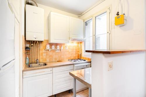 une petite cuisine avec des armoires blanches et un évier dans l'établissement GuestReady - Parisian Bliss near Notre-Dame, à Paris