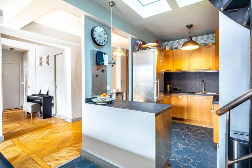 une cuisine avec des armoires en bois et une horloge au mur dans l'établissement GuestReady - Parisian Charm near Sacré-Cœur, à Paris