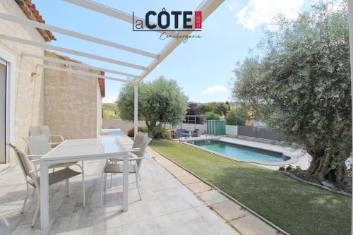 une terrasse avec une table et des chaises blanches ainsi qu'une piscine dans l'établissement Villa Côte Bleue, à Ensuès-la-Redonne